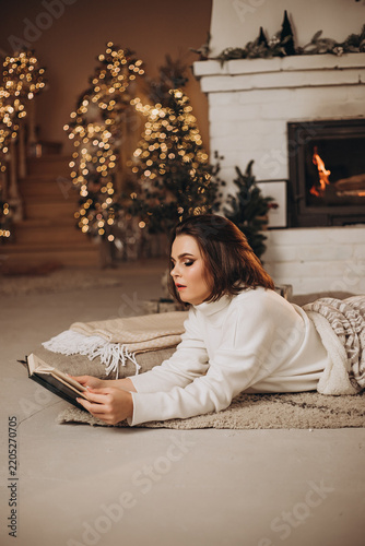 Canvastavla Cozy holiday evening by the fireplace with a woman reading a book
