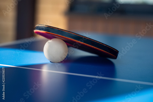Table tennis paddle and ball on blue ping pong table