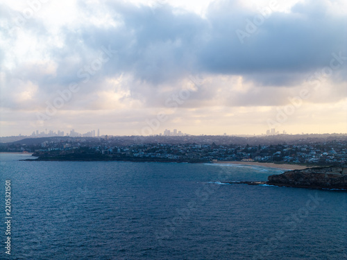 Aerial view of the coastline at Dee Why with the distant Sydney skyline visible under a cloudy sky in Dee Why, New South Wales, Australia.