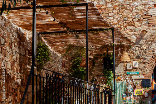 terrace and stone wall shaded by a reed canopy that allows lines of light to filter through, and a string of bulbs for nighttime lighting.