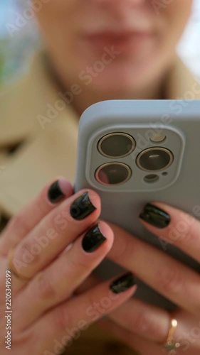 woman hands with black manicure holding smartphone close up vertical view, female hands typing on mobile phone in grey case, close up of female hands holding smartphone with triple camera