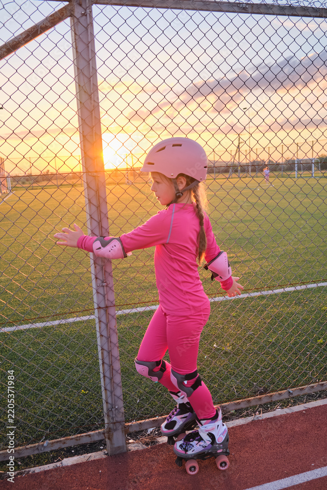 Obraz premium Young girl roller skate outdoor sport park sunset play active childhood