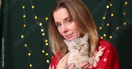 Woman posing with a gray British Shorthair cat, cozy holiday moment.