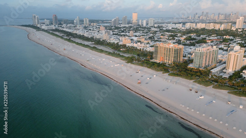 Aerial view of the expansive sandy coastline, turquoise ocean waters, and the iconic skyline of hotels and residential buildings along the shore in Miami Beach, Florida, United States.