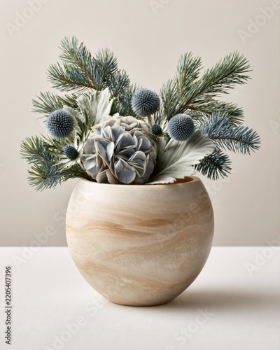 Elegant floral arrangement featuring blue hydrangea, complemented by spherical blue echinops, sculptural eryngium thistles, and airy branches of blue spruce in a handcrafted matte vase.