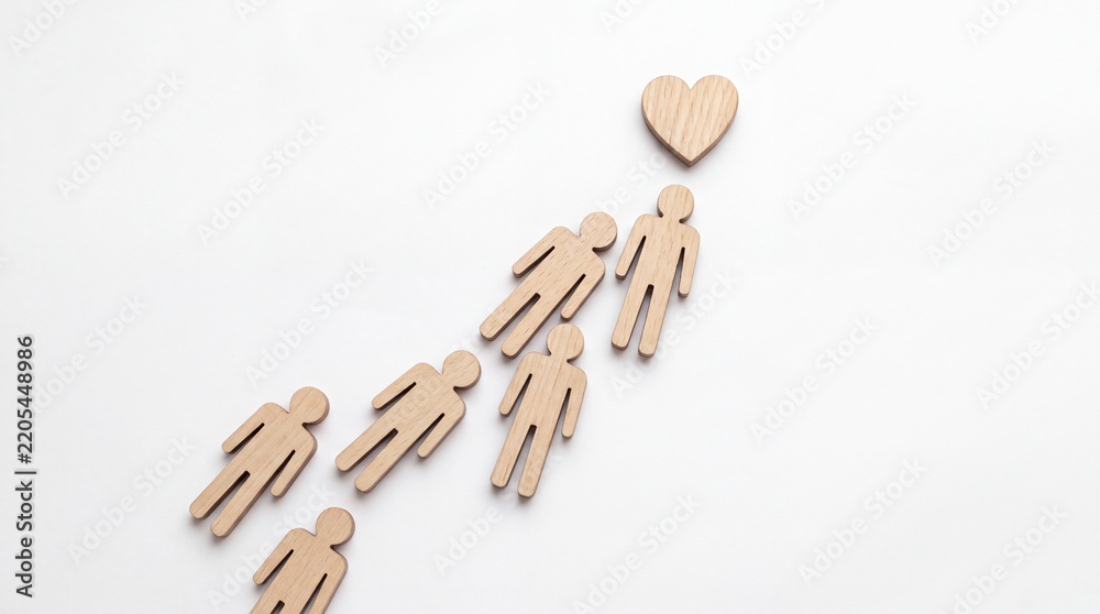 Obraz premium Minimalist Concept of People Moving Toward Love or Compassion Symbolized by Wooden Human Figurines and a Heart Shape on a White Background for Charity, Unity, and Social Support Theme.