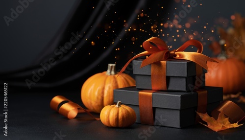Stacked gifts with pumpkins and autumn leaves on a dark background.
