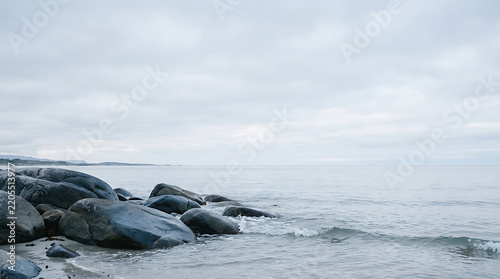 Large dark rocks on the seashore under a cloudy sky with ocean rocks