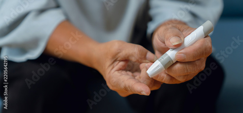 Elderly woman using a lancet for blood sugar testing at home, diabetes care and glucose monitoring.