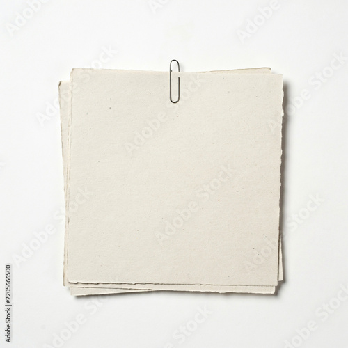 Thick stack of rustic paper sheets secured with metal stationery recycled fastener material business background organizer workshop resource template composition as isolated object