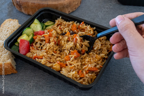 Obraz na płótnie Person eating rice pilaf from takeaway box close up