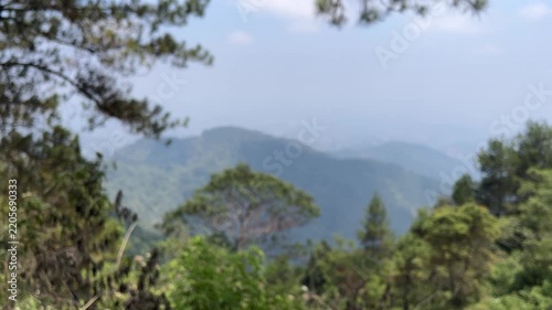 A scenic view of a valley in Tawangmangu, Central Java, Indonesia showing beautiful scenery, pine, trees. hills. blue sky, clouds. eco, ecology, environment. day. bright. blur, blurry, blurred