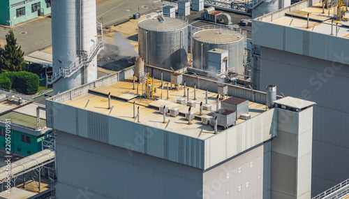 Aerial view of an industrial power generation building featuring rooftop ventilation equipment, large storage tanks, and steam infrastructure, Chivasso, Piedmont, Italy.