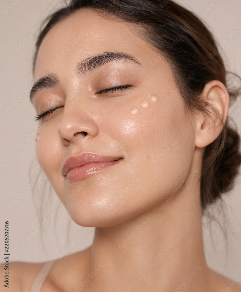 Obraz premium Woman Applying Skincare Serum Drops to Cheek