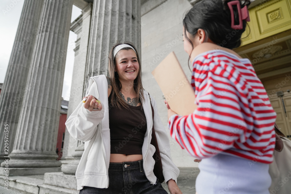 Obraz premium Female students chatting on campus in front of university building