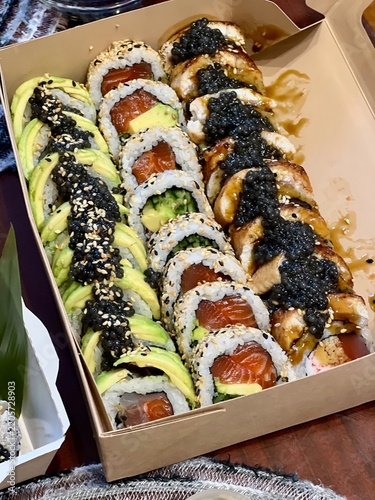 Detailed shot of a sushi container packed with a colorful variety of fresh sushi rolls, maki, and nigiri. An appetizing fast food meal ready for delivery, catering, or takeaway.