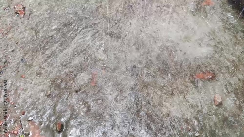 ​Heavy rain falling and splashing on a wet concrete surface with broken bricks
