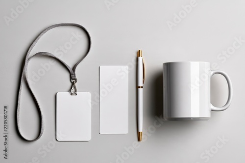 Corporate identity mockup featuring white mug and id badge on grey backdrop in a minimalist top-down view for brand design marketing