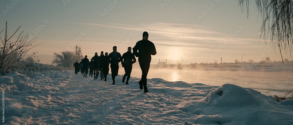 Obraz premium Group of runners jogging on snowy trail at sunrise