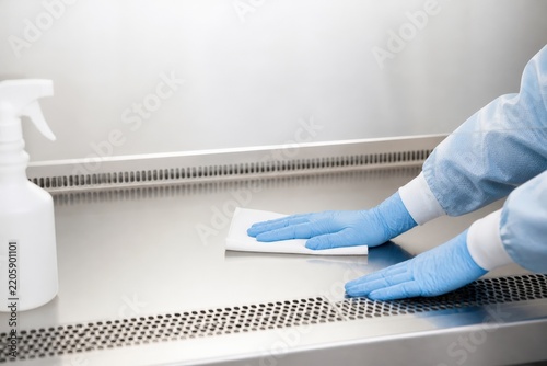 Sterile compounding pharmacy hands cleaning an empty hood surface