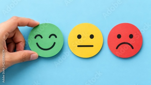 Hand holding green happy face icon on World Smile Day against a blue background with neutral and sad icons