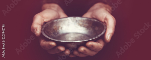 Hands holding empty metal bowl, symbolizing poverty, hunger, and a plea for help or financial aid