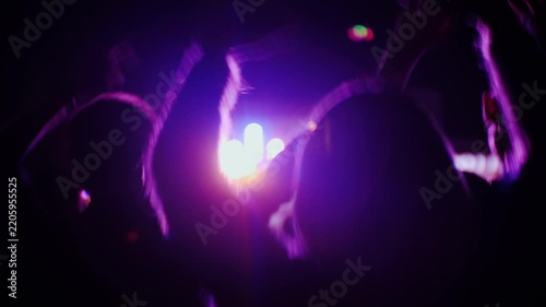 Crowd cheering and dancing at a concert with colorful lights and lasers.