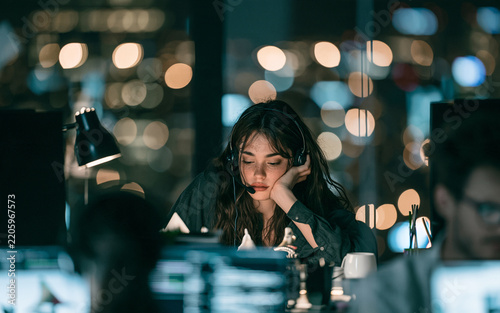 Focused woman studying laptop screen in city office at night, remote work concentration and technology research concept, professional female portrait