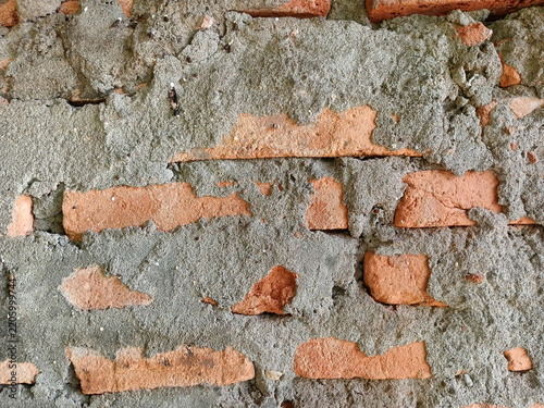 Rough texture of unfinished brick wall with messy grey cement mortar