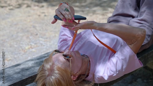 Mature woman relaxing on a park bench using her smartphone