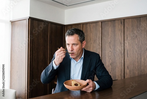 Middle-aged businessman in an elegant suit enjoying a gourmet poached pear dessert at a luxury restaurant table