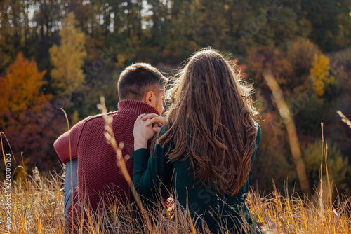 Couple sitting together in autumn forest setting.