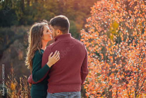 Couple embracing outdoors during autumn season.