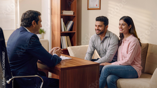 Indian Financial Advisor Consulting Young Couple in Traditional Attire Inside Modern Office