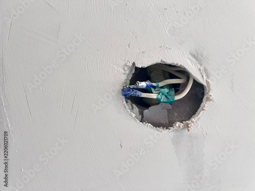Unfinished interior renovation: electrical wiring preparation in a plasterboard hole with insulation tape, space for message