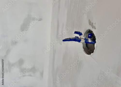 Electrician work in progress: bare wires with protective tape emerging from a drywall socket hole, copy space