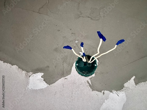 Drywall electrical outlet hole with taped wires on a pale wall, renovation concept with copy space