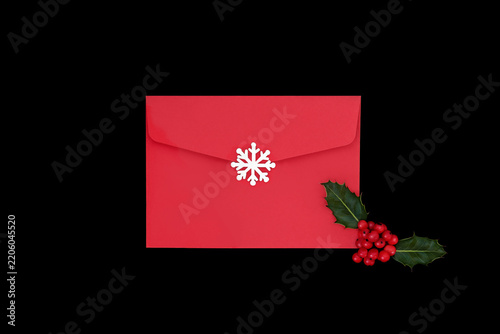 Christmas mail art concept red envelope on black with snowflake, holly red berries leaves. Seasonal Xmas holiday elements with traditional symbols.