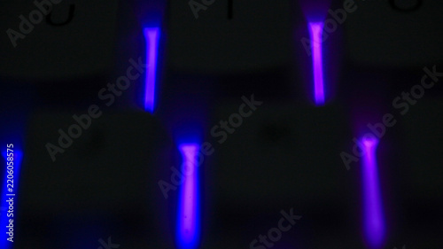 Blurred macro of a backlit mechanical keyboard glowing blue and purple, RGB gaming technology background