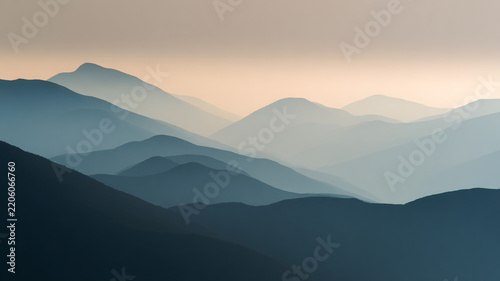 layered mountain silhouettes fading into mist, soft gradient tones, minimal composition, atmospheric depth