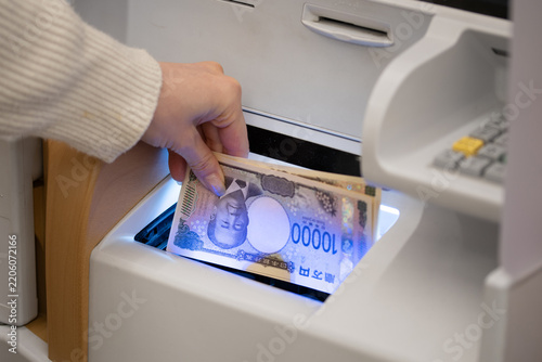 銀行やコンビニのATMで一万円札（新紙幣）を入出金する女性の手元