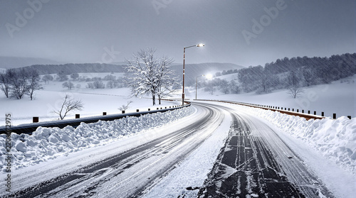 Serene Winding Snowy Road Through Winter Landscape with Streetlights
