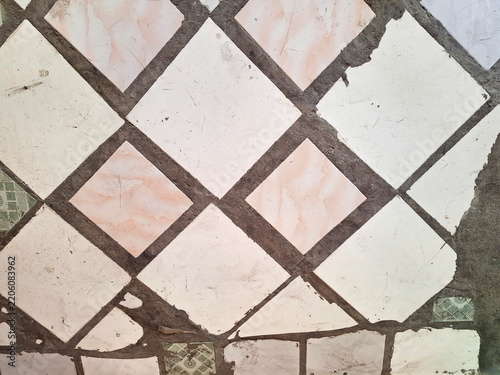 Old white and pink diamond patterned floor tiles with grunge texture.