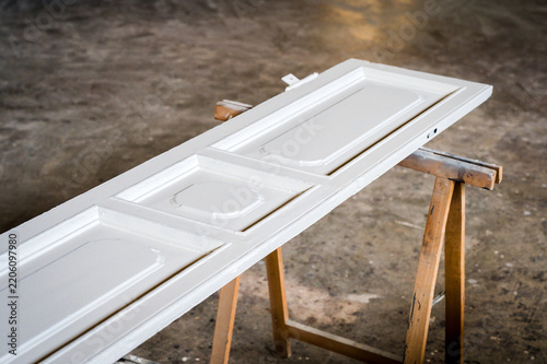 White paneled door resting on sawhorses in workshop