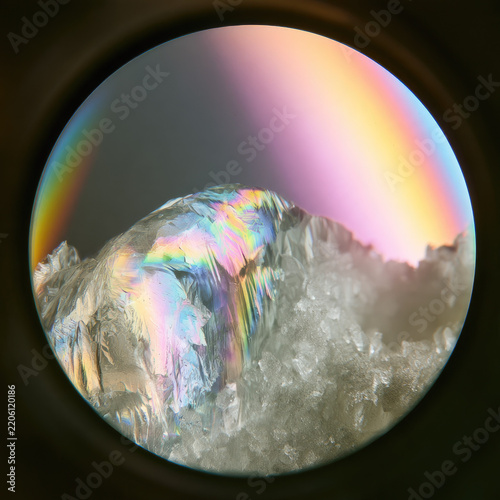 Sucrose crystal polarized microscope macro view with iridescent rainbow interference color and crystalline facet detail creating scientific abstract texture