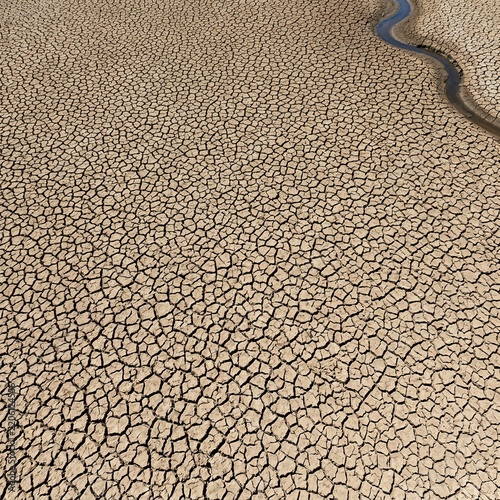 Aerial View of Cracked Dry Earth with a Narrow Stream of Water
