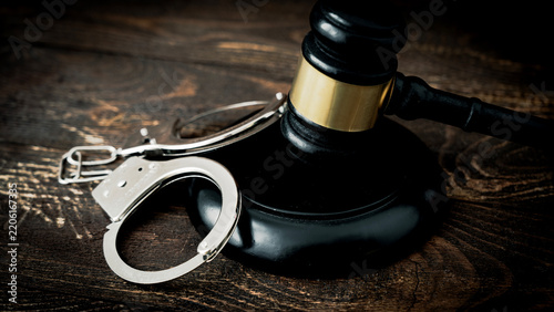 Wooden gavel rests beside silver handcuffs