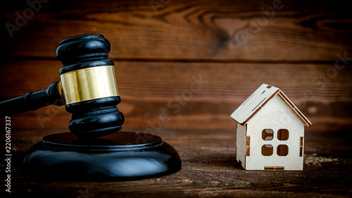 Wooden gavel rests beside miniature house