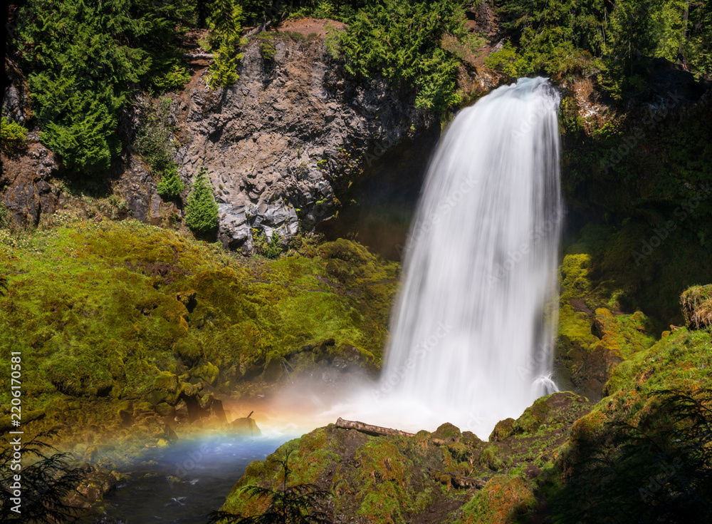Fototapeta premium Sahalie Falls cascades powerfully down basalt cliffs in Oregons Willamette National Forest, creating mist and a rainbow.