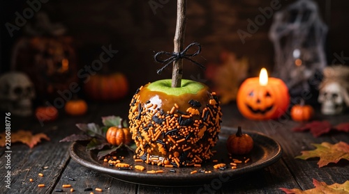Gourmet caramel apple coated in sprinkles served on a rustic plate at halloween